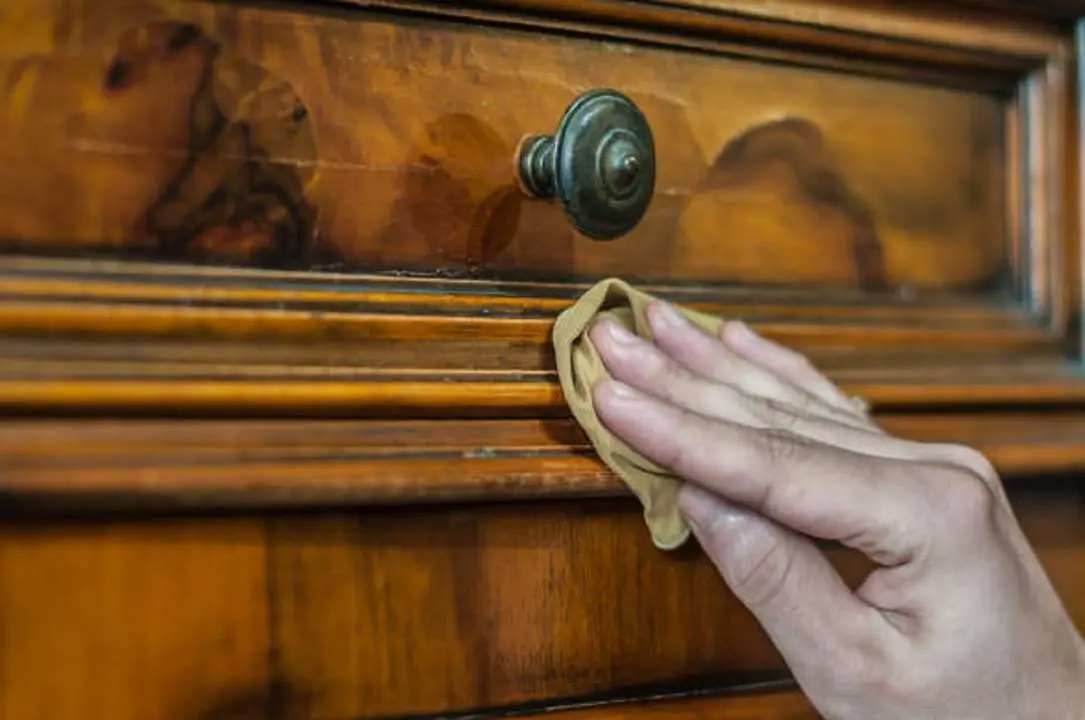 Hand applying oil and wax on a old wood furniture