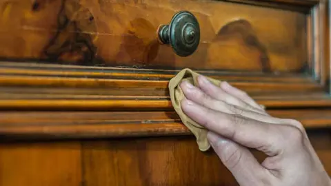 Hand applying oil and wax on a old wood furniture